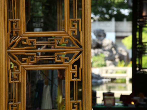 adorned Chinese window frame in front of Chinese garden view.